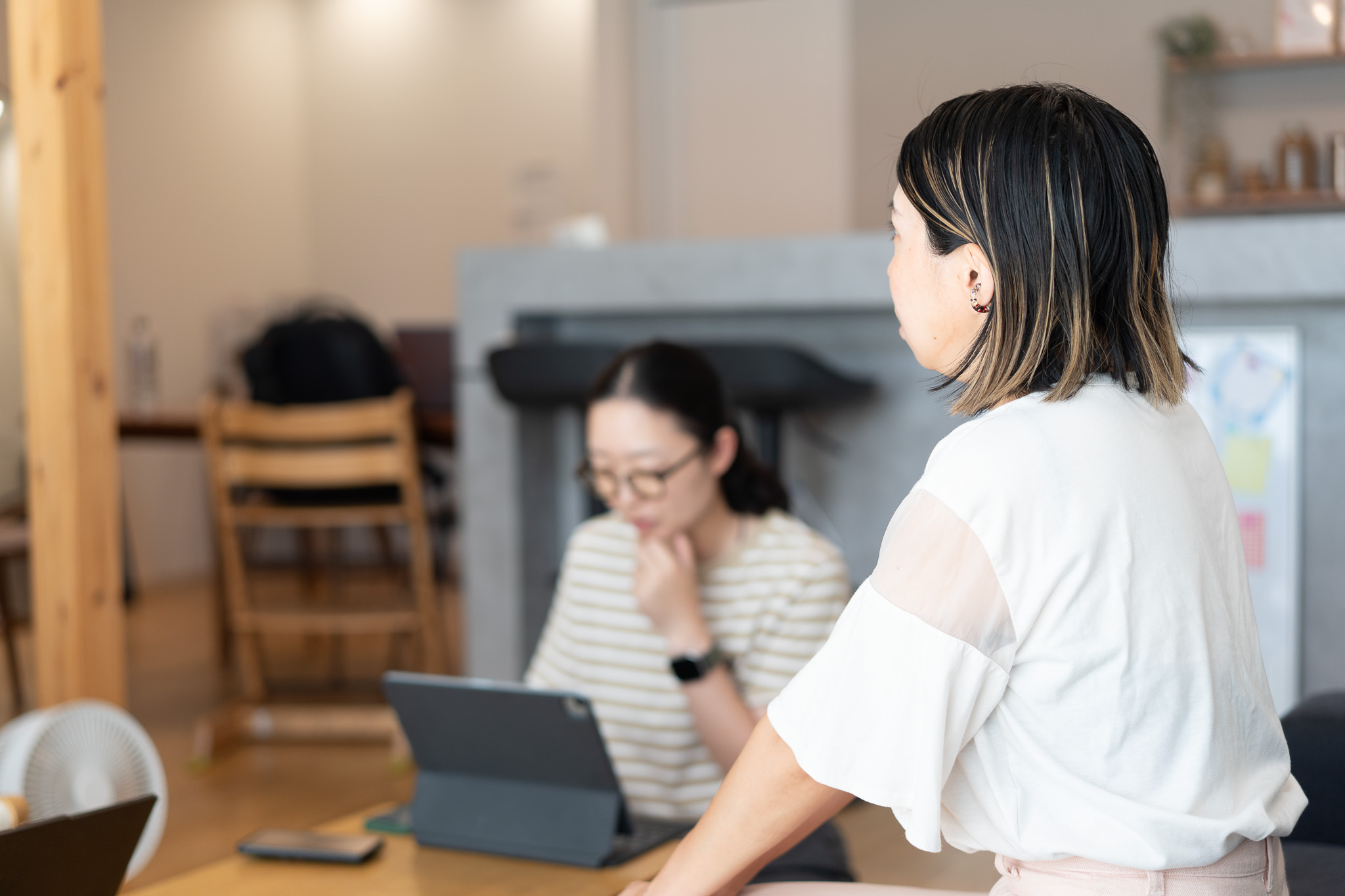 明るい室内で、タブレットを前にした女性と、その向かいに座る女性が話している様子