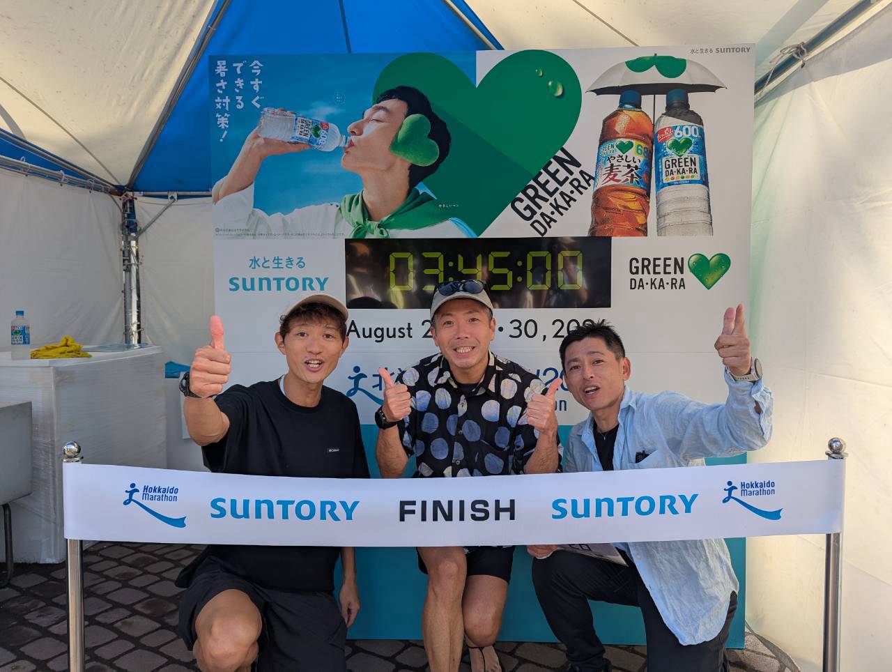 北海道マラソンのフィニッシュゲートを模したエキスポの撮影ブースで、3人が親指を立てて並んでいる