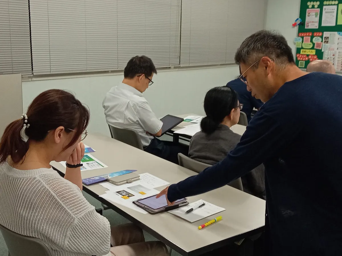 参加者のタブレットの画面を講師が指しながら説明している
